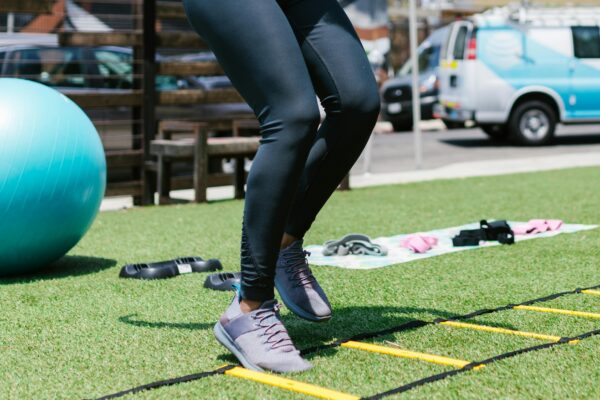 Close-up of a person exercising with a speed ladder in an outdoor setting.