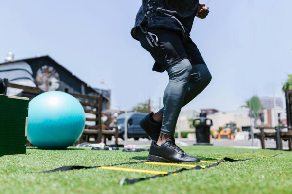 Person exercising outdoors with fitness gear and agility ladder on grass.